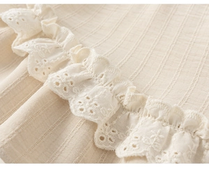Vue détaillée du tissu en coton avec broderie anglaise florale et bordure volantée