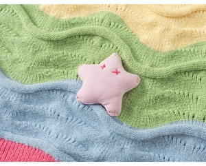 Close-up of a pink plush star with red embroidery on a rainbow knit background