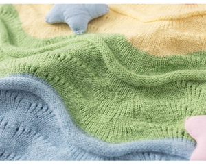 Detail of colorful rainbow knit vest with wave patterns and soft star fabric ornament