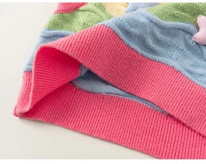 Detail of colorful cable knit vest featuring 3D star accents and pink ribbed hemline