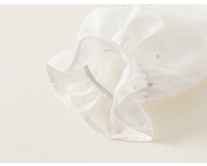 Detail of ruffle cuff with colorful dots on a breathable white cotton kids shirt