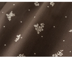 Gros plan sur un tissu marron foncé avec imprimé floral et petits pois pour la texture