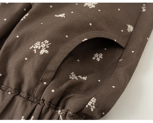 Détail du tissu en coton floral marron avec coutures de poche précises et bords à volants