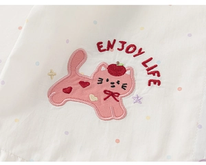 Detail of cartoon cat embroidery with Enjoy Life text on a white cotton girl shirt