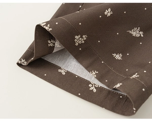 Détail macro du tissu floral en coton marron foncé avec couture précise pour filles
