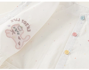 Detailed close-up of white girl's shirt with colorful polka dots and cute bear embroidery