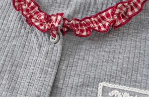 Detail of grey ribbed knit top with red plaid ruffled collar and lace embroidery patch