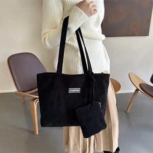 Detail of black corduroy tote bag set with white fashion label and matching mini pouch