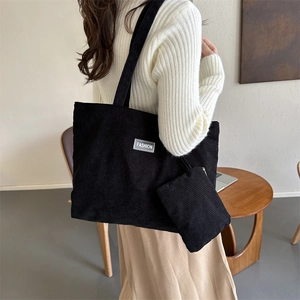 Detail of black corduroy tote bag with fashion label and small matching pouch