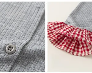 Close-up of gray ribbed fabric featuring button closure and red checkered ruffled cuffs