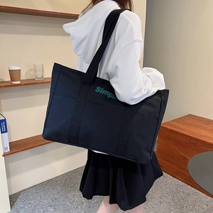 Minimalistische schwarze Canvas-Einkaufstasche mit grünem Simple-Schriftzug und breitem Gurt