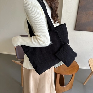 Detail view of black corduroy tote bag with vertical texture and small zipper pouch