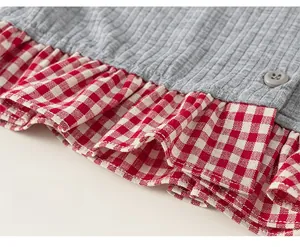 Detail of grey ribbed fabric stitched with red plaid ruffle hem and decorative button