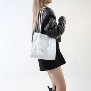 Close-up of minimalist white PU tote bag with grain texture and mini coin purse detail