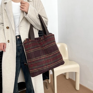 Detail of red and green plaid woolen tote bag with brown fabric shoulder strap for winter