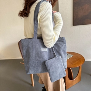 Gray corduroy tote bag with small pouch and fashion label shown on model