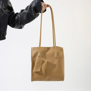 Detail of tan lychee textured faux leather tote bag with small envelope pouch accessory