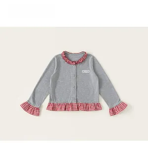 Detail of grey ribbed knit kids top featuring red checkered ruffled hem and sleeve cuffs