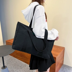 Lifestyle-Foto der schwarzen Canvas-Tragetasche mit verstellbarem Schultergurt und Seitentasche