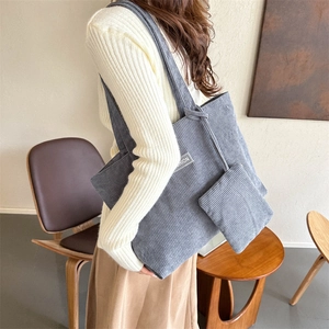 Detail of grey-blue corduroy tote bag showing its ribbed texture and fashion logo patch