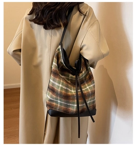 Detail of wool fabric tote bag with green plaid pattern and black leather strap