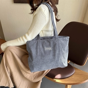 Detail of grey-blue corduroy shoulder bag with fashion label and textured fabric