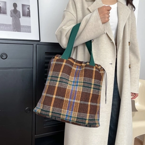 Detail of vintage plaid tote bag with thick fabric texture and green fabric handles
