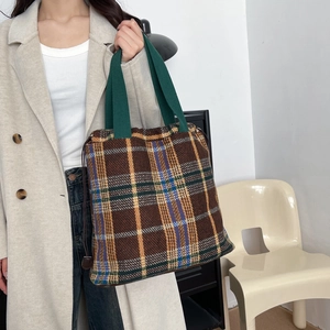 Detail of wool plaid tote bag with drawstring closure worn with a beige winter coat