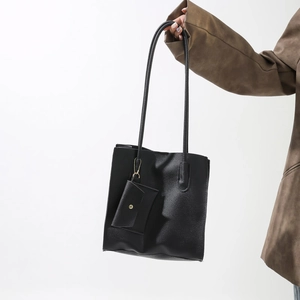 Detail of minimalist black pebbled leather tote bag with a small hanging envelope coin pouch