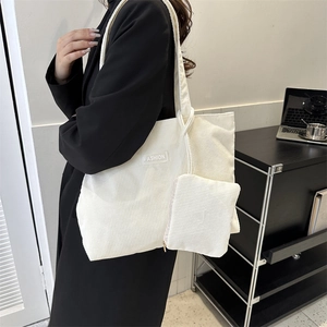 Detail of model wearing cream corduroy tote bag with fashion patch in lifestyle setting