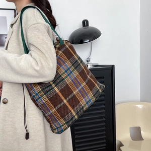 Detail of tweed checkered tote bag on beige coat with retro plaid wool texture