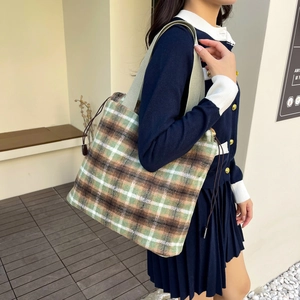 Detail of wool plaid tote bag in green and brown with shoulder strap on model
