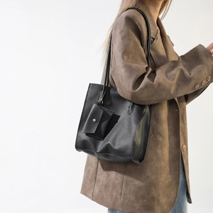 Detail of minimalist black PU leather tote bag with gold chain pouch on model shoulder