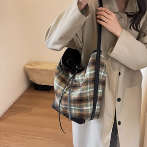 Close-up of vintage plaid wool shoulder bag with black drawstring and leather trim detail