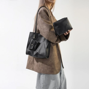Close-up of black lychee grain leather tote bag with small pouch and textured surface