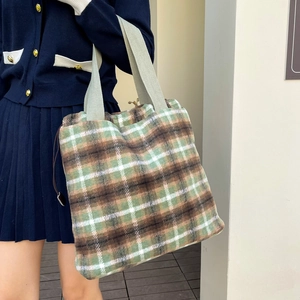 Detail of green and brown wool checkered tote bag with woven strap and drawstring side
