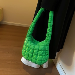 Close-up of vibrant lime green quilted puffer hobo bag styled with a minimalist outfit