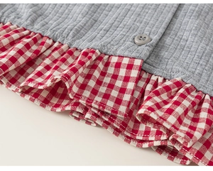Detail of grey ribbed knit fabric with red gingham ruffle hem and matching button