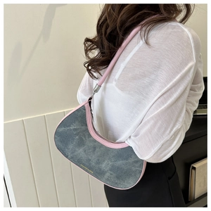 Side view of grey-blue denim hobo bag with pink leather straps worn by a model