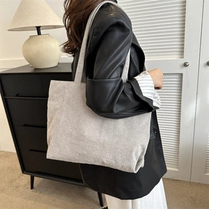 Detailed texture of light grey corduroy tote bag worn on shoulder by model