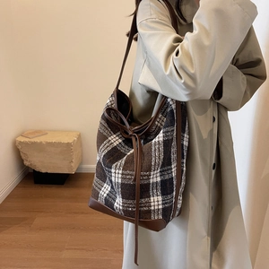 Detail of checkered wool tote bag with leather trim and drawstring in a cozy autumn setting