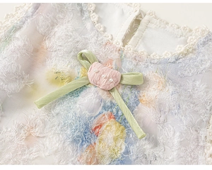Détail d'une robe fleurie pour fille avec col en dentelle, nœud satiné et perles