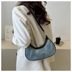 Detail of blue denim hobo bag with black leather trim and gold fashion text