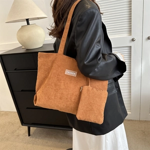 Detail of caramel corduroy tote bag with textured stripes and small zip pouch on model