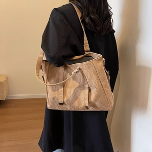 Detail view of large beige tote bag with pleated texture and adjustable shoulder strap
