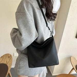 Detail view of black lychee grain PU leather crossbody bag on female model