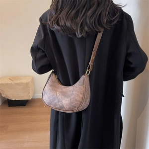 Sac à bandoulière vintage en similicuir marron porté à l'épaule par un mannequin
