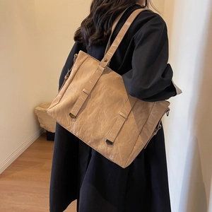 Chic beige tote bag with pleated texture and stud details shown in a lifestyle setting