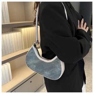 Detail of blue denim and white leather crescent shoulder bag worn on a black blazer