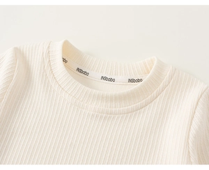 Détail d'un pull en maille côtelée crème avec col rond et texture verticale délicate